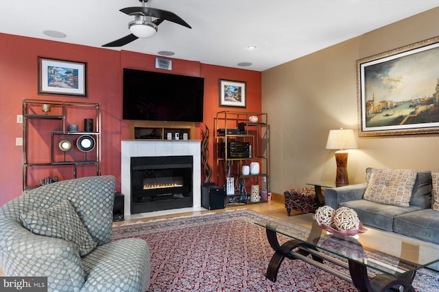 living room with a fireplace with flush hearth, wood finished floors, baseboards, and a ceiling fan