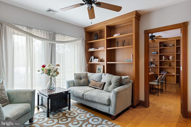 living area featuring light wood finished floors, visible vents, and a ceiling fan