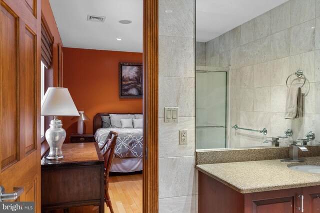 full bathroom featuring visible vents, ensuite bathroom, a shower with shower door, vanity, and tile walls