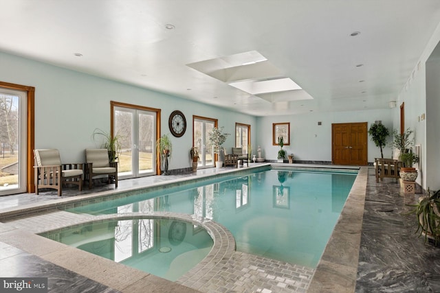 view of swimming pool with a skylight and a pool with connected hot tub