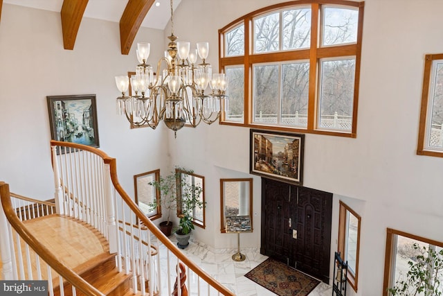 entrance foyer with marble finish floor, beam ceiling, a towering ceiling, an inviting chandelier, and stairs