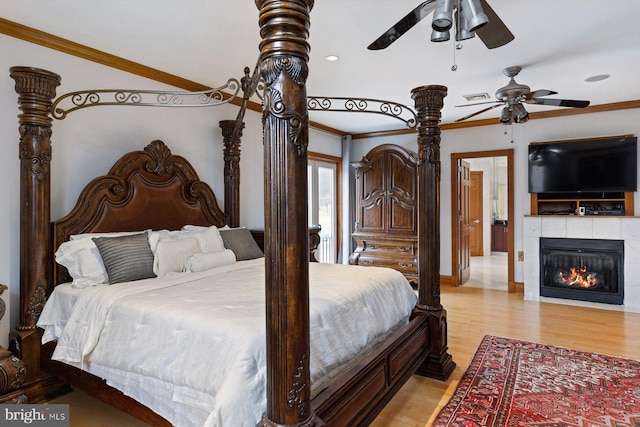 bedroom with light wood-style flooring, visible vents, a ceiling fan, ornamental molding, and a tiled fireplace