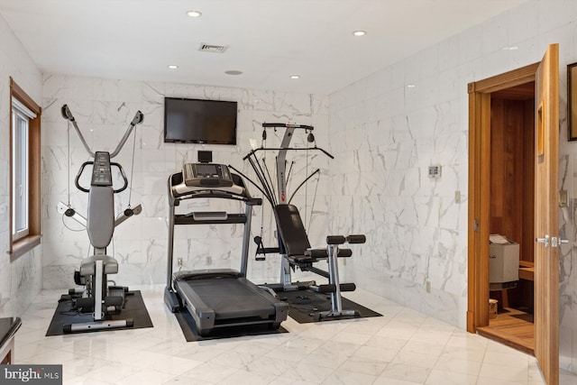 exercise area featuring stone wall, tile walls, and recessed lighting