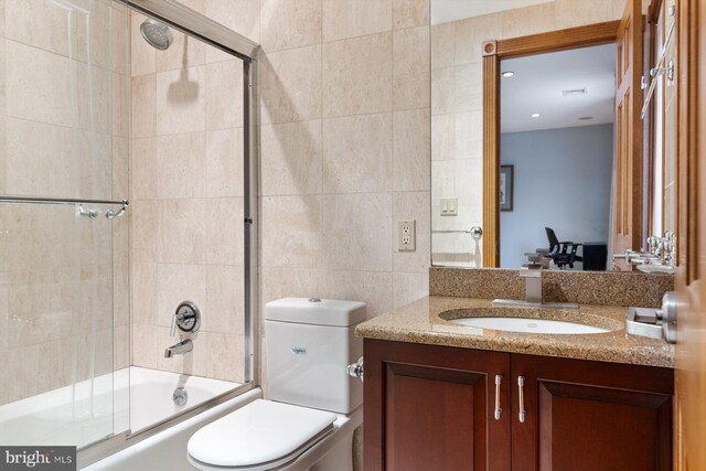 full bath with toilet, enclosed tub / shower combo, tile walls, and vanity