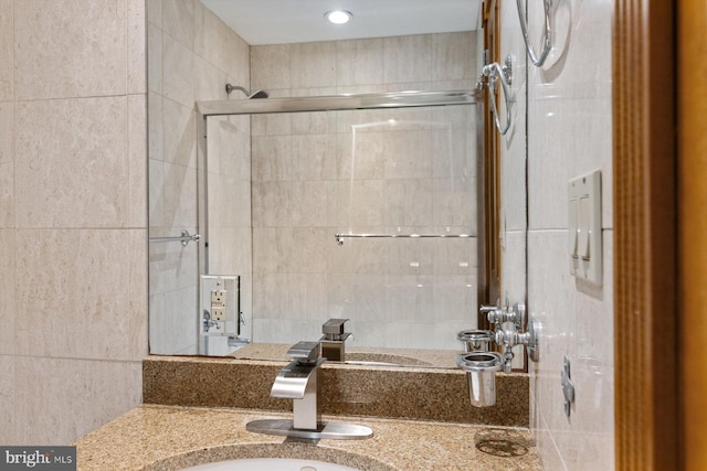 bathroom featuring tiled shower, vanity, and tile walls