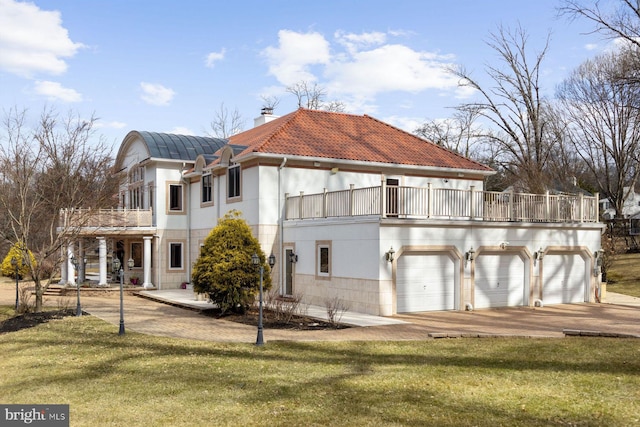 exterior space featuring a garage, a yard, a chimney, and a tile roof