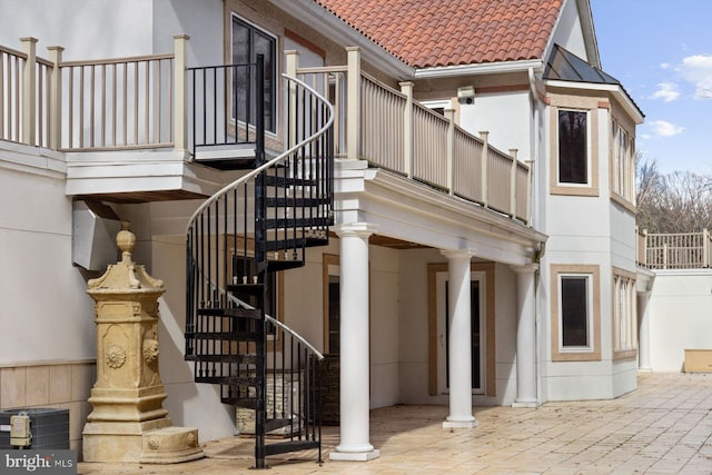 exterior space featuring a patio, central air condition unit, a tile roof, and stucco siding