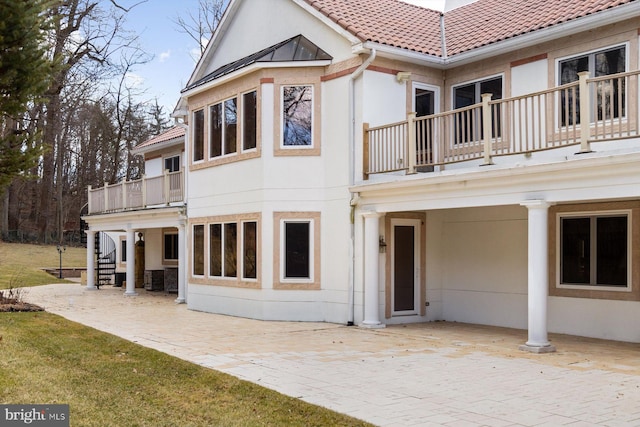 back of property featuring metal roof, a tiled roof, stairs, a patio area, and stucco siding