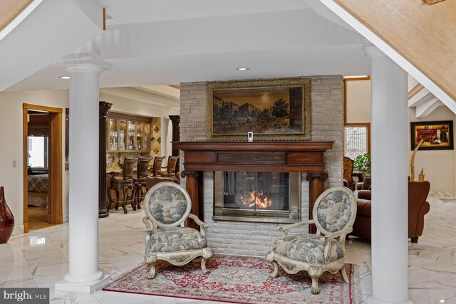 living area with marble finish floor, a fireplace, and ornate columns