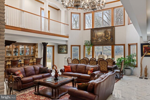 living area with a chandelier, marble finish floor, and a towering ceiling