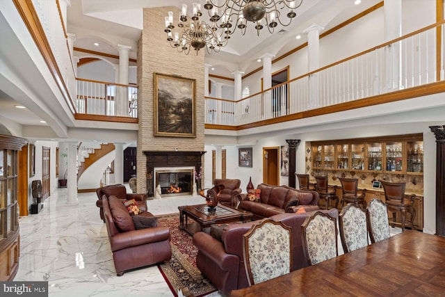 living area featuring a large fireplace, marble finish floor, and ornate columns