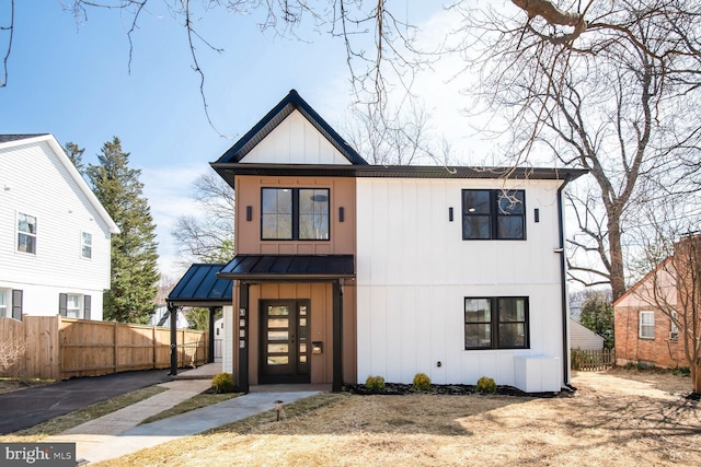 modern farmhouse with board and batten siding, metal roof, a standing seam roof, and fence