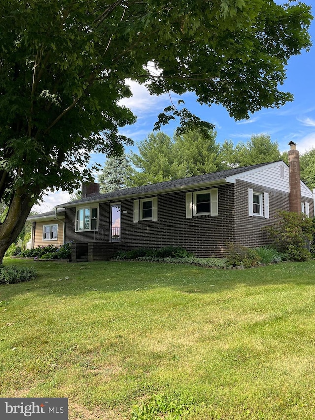 ranch-style home with a chimney, a front lawn, and brick siding