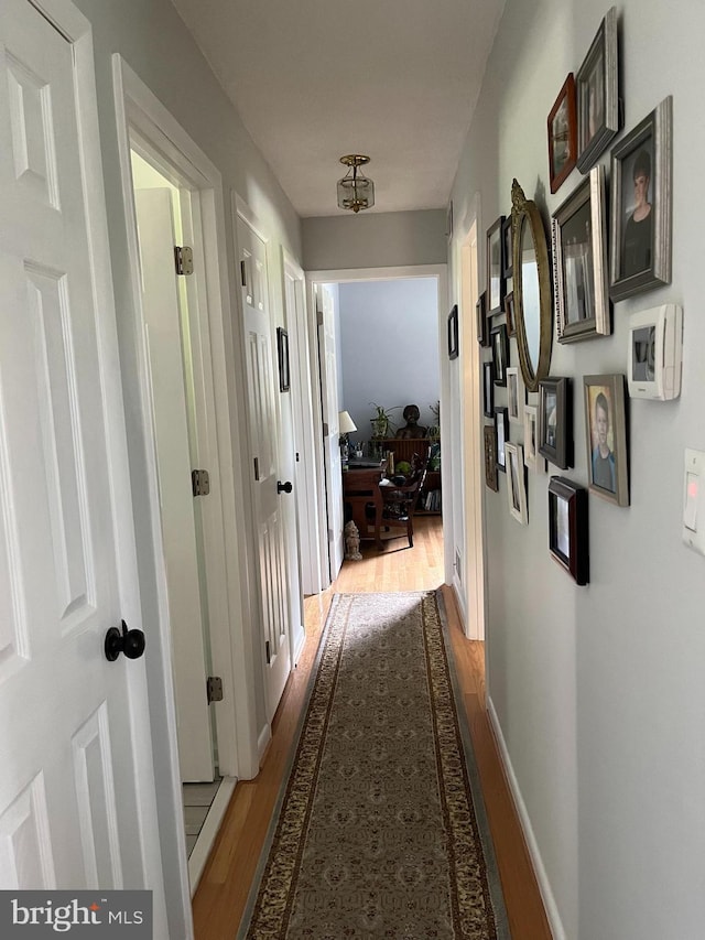 corridor featuring baseboards and wood finished floors