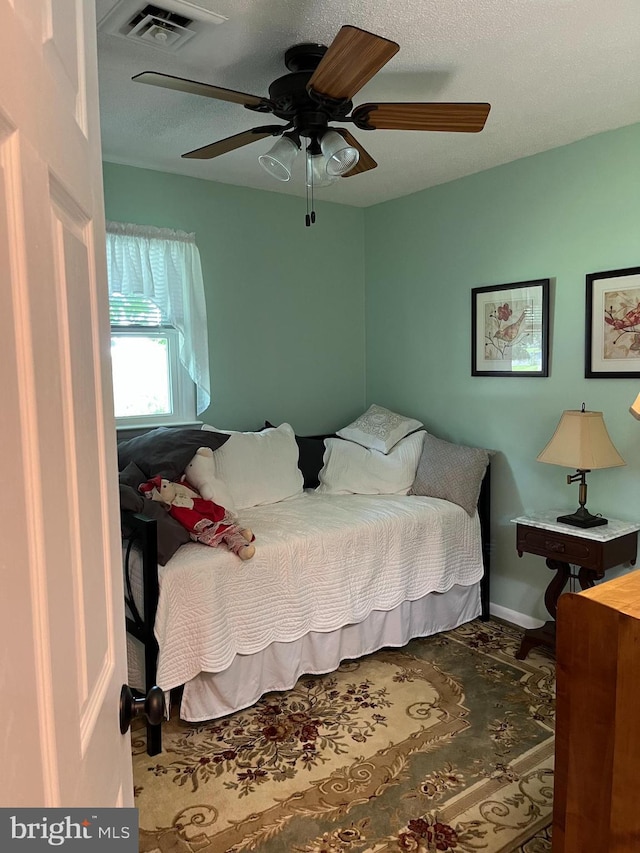 bedroom featuring visible vents, ceiling fan, a textured ceiling, and baseboards