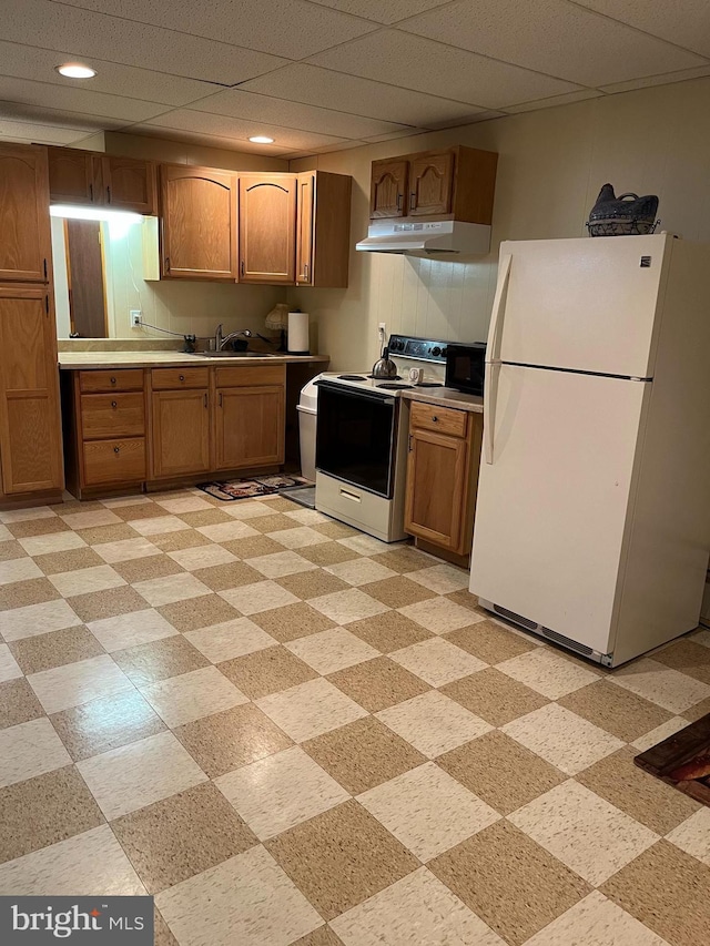 kitchen with under cabinet range hood, electric range, a sink, freestanding refrigerator, and brown cabinets