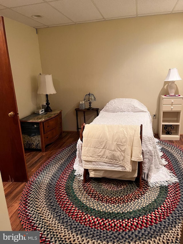 bedroom with a paneled ceiling and wood finished floors