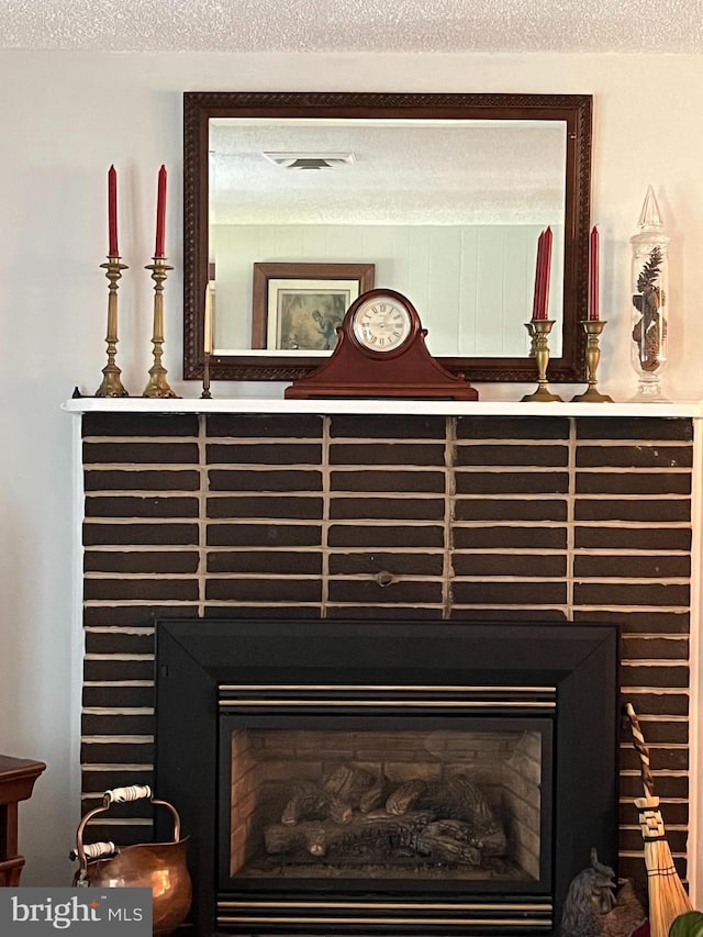 details with a textured ceiling, a fireplace, and visible vents