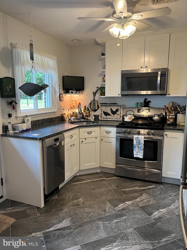 kitchen featuring appliances with stainless steel finishes, white cabinetry, a sink, and a textured ceiling