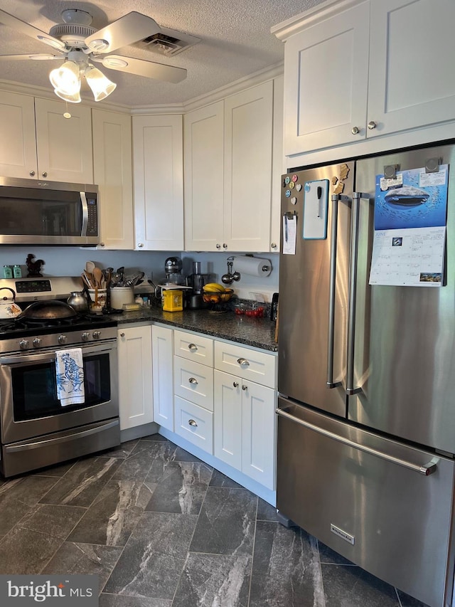 kitchen with a textured ceiling, stainless steel appliances, ceiling fan, and white cabinetry