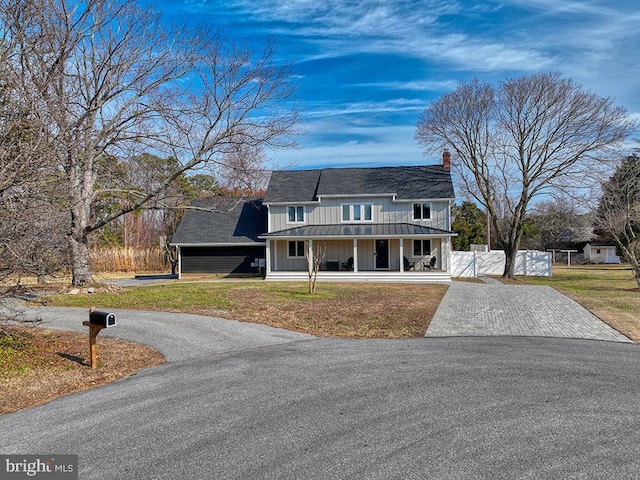 view of front facade featuring covered porch, a gate, aphalt driveway, and board and batten siding