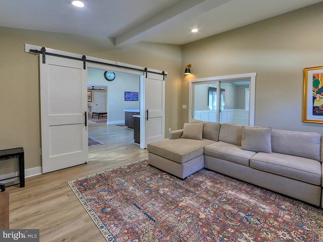 living room featuring baseboards, a barn door, recessed lighting, and light wood-style floors