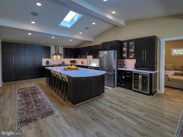 kitchen featuring high quality fridge, wine cooler, dark cabinets, light countertops, and lofted ceiling with skylight