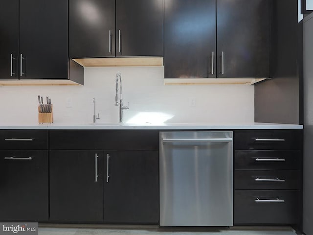 kitchen featuring decorative backsplash, dark cabinetry, light countertops, and dishwasher