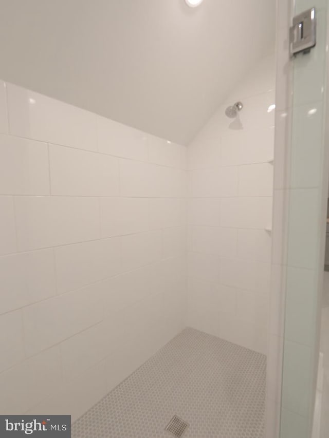 bathroom featuring vaulted ceiling and tiled shower