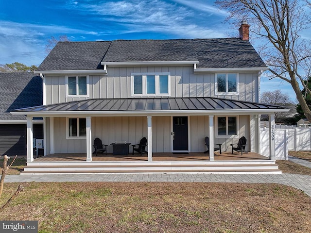 back of house featuring covered porch, a standing seam roof, board and batten siding, and roof with shingles