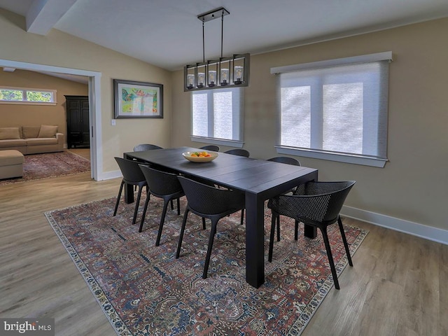 dining room with lofted ceiling with beams, wood finished floors, a wealth of natural light, and baseboards