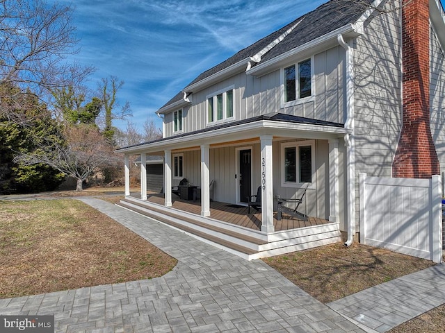 view of front of home with covered porch, a chimney, and roof with shingles