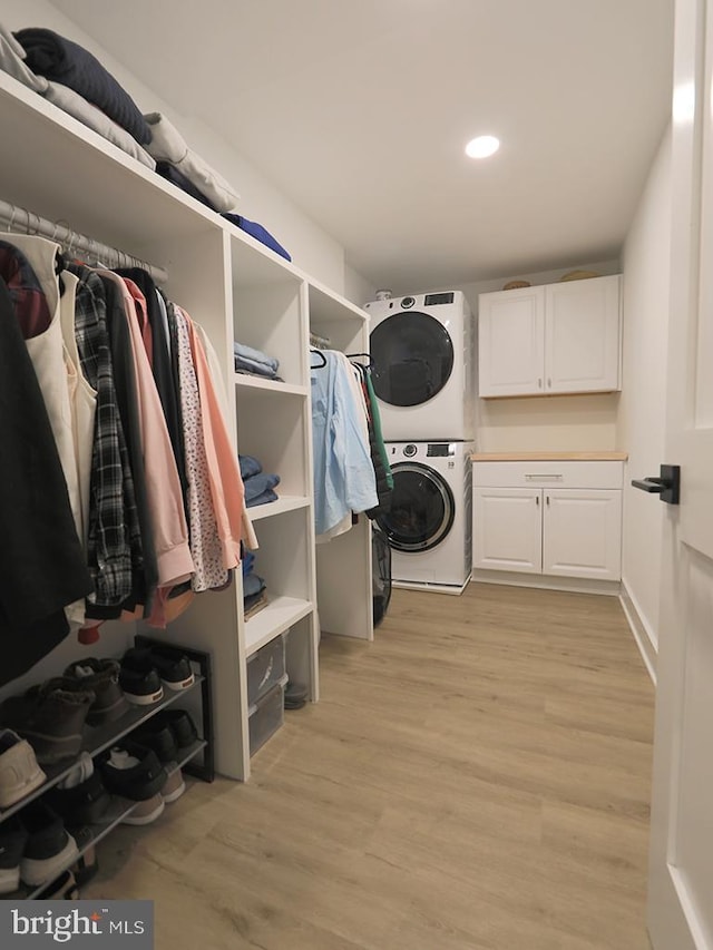 spacious closet featuring stacked washer and dryer and light wood-style floors