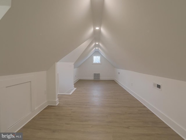 bonus room featuring lofted ceiling, wood finished floors, visible vents, and baseboards