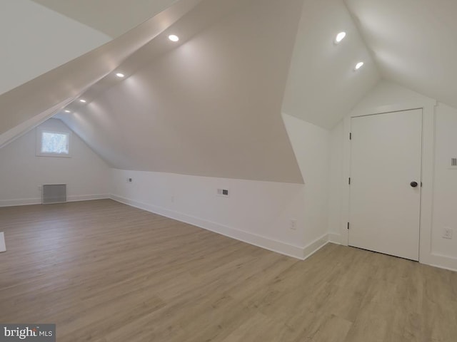 additional living space with lofted ceiling, light wood-style flooring, visible vents, and baseboards