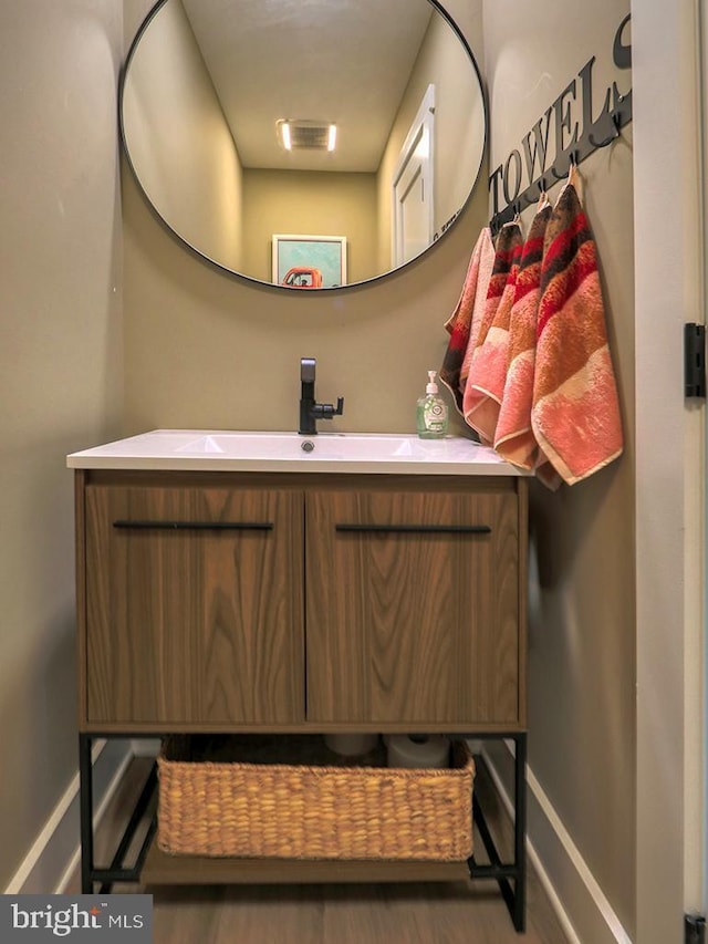 bathroom with baseboards, wood finished floors, and vanity