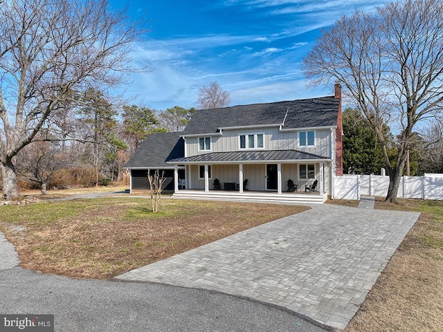 view of front of property with a porch, a standing seam roof, fence, and decorative driveway