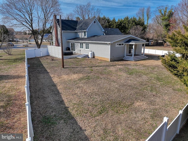 back of house featuring a fenced backyard and a lawn