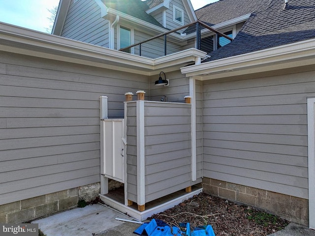 doorway to property featuring roof with shingles