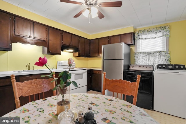 kitchen with dark brown cabinetry, under cabinet range hood, a sink, freestanding refrigerator, and white range with electric cooktop