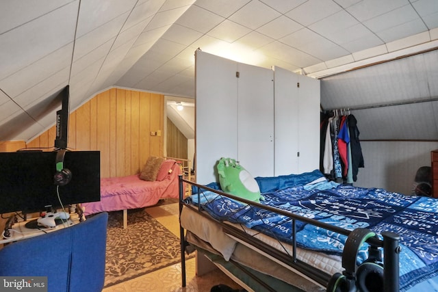 bedroom with lofted ceiling, a closet, and wood walls