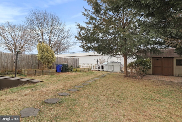 view of yard featuring a storage shed, a garden, fence, and an outdoor structure