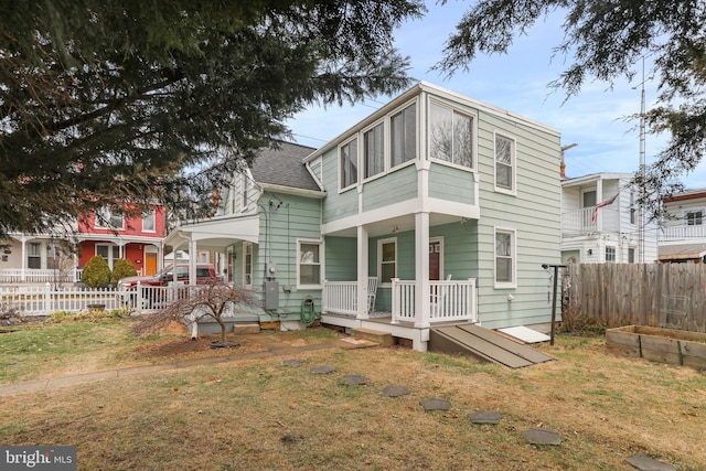 back of house with covered porch, a shingled roof, fence, and a yard