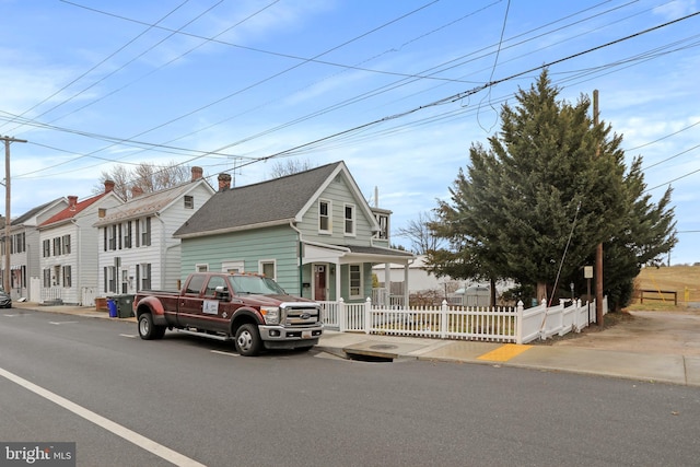 view of front facade featuring roof with shingles, a fenced front yard, and a residential view