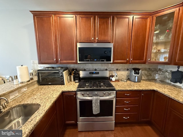 kitchen featuring a toaster, appliances with stainless steel finishes, tasteful backsplash, and a sink