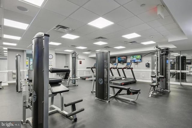 gym with visible vents, a decorative wall, and a drop ceiling