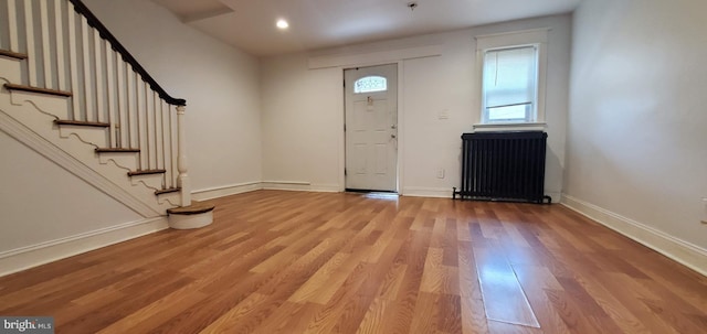 entryway featuring baseboards, radiator heating unit, stairs, light wood-style floors, and recessed lighting