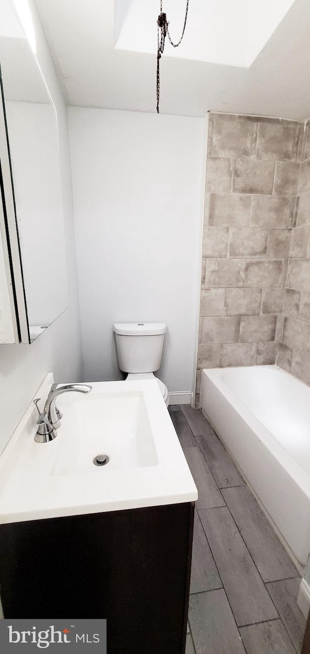 bathroom featuring toilet, bathing tub / shower combination, wood finished floors, and vanity