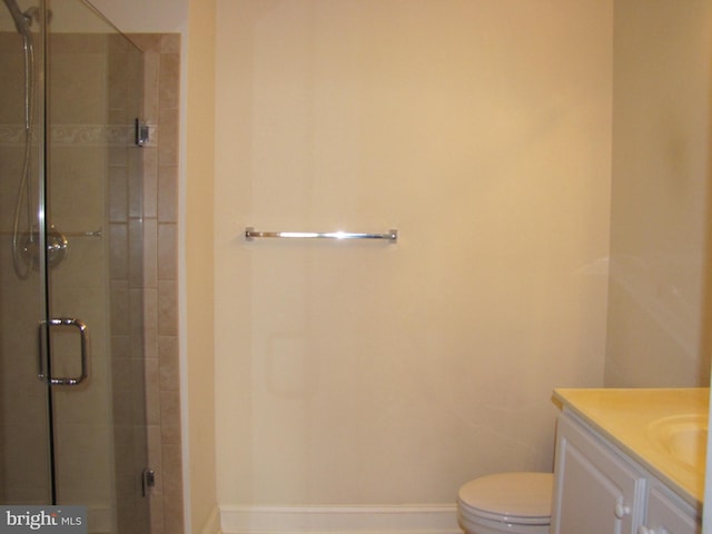 full bath featuring toilet, a shower stall, vanity, and baseboards