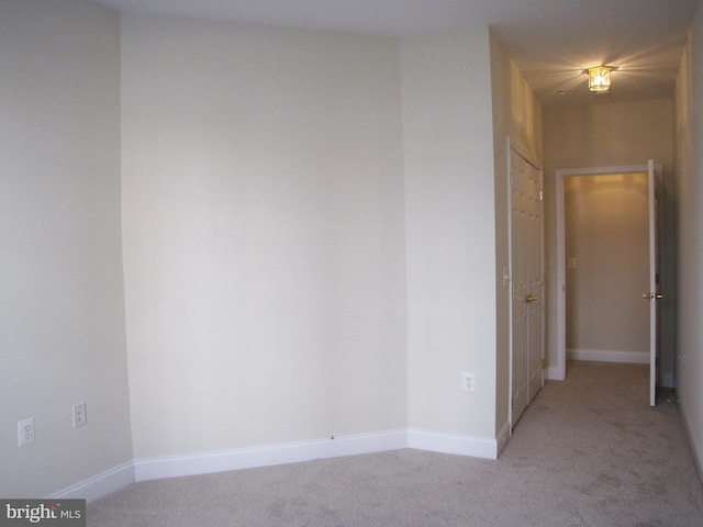 empty room featuring baseboards and light colored carpet